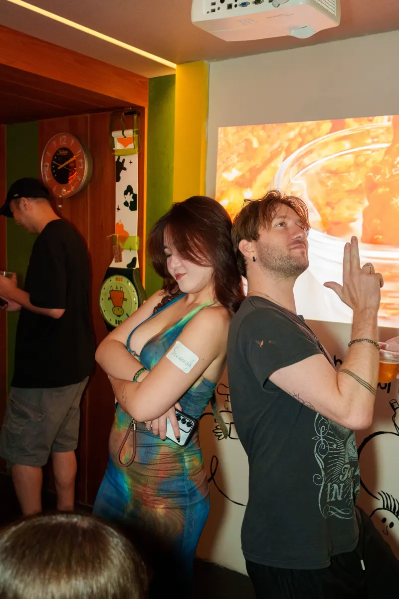 Two guests posing back to back at a social event
