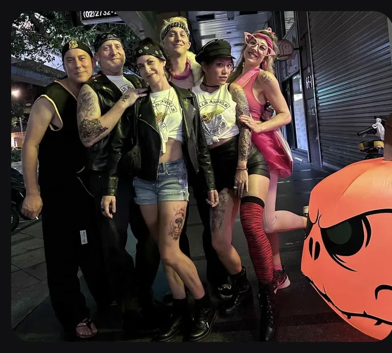 A group in costumes posing beside a pumpkin decoration