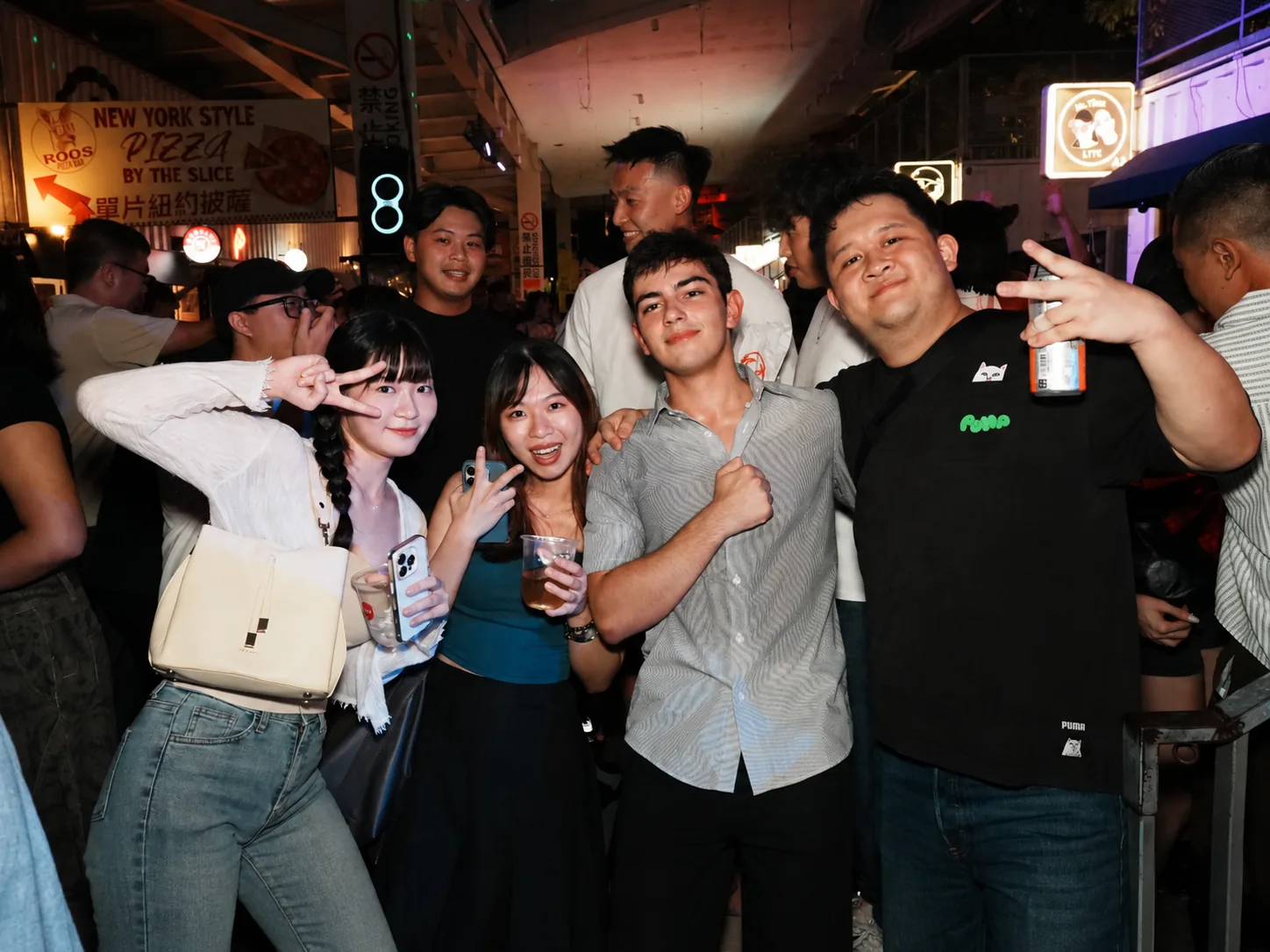 A group of guests smiling and making peace signs at a bar
